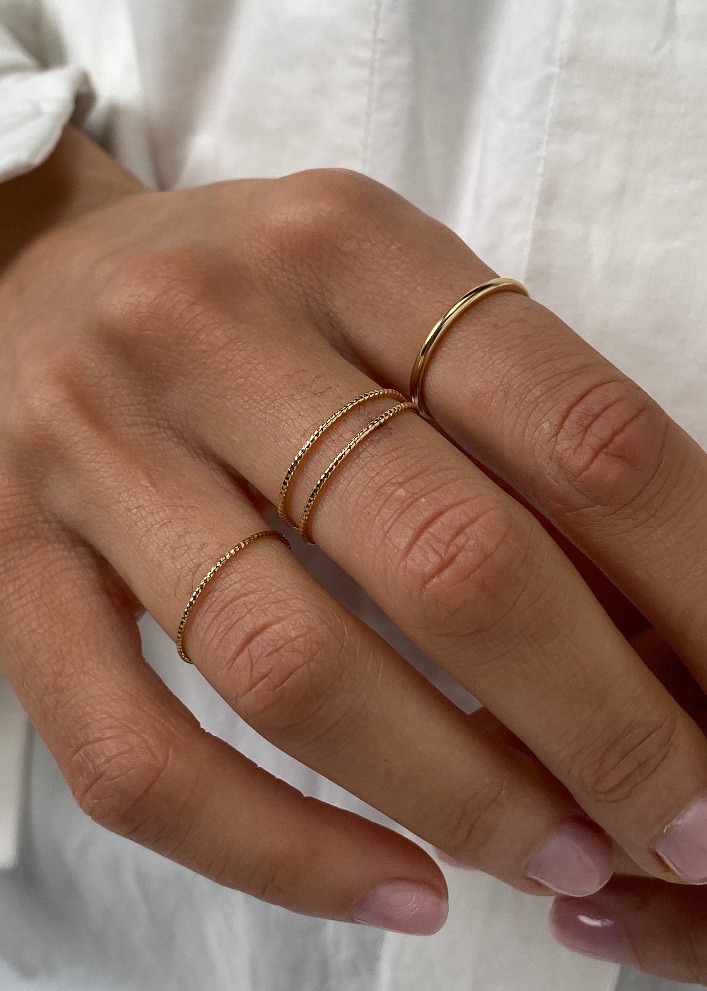 Close-up of a hand wearing gold rings on a white background